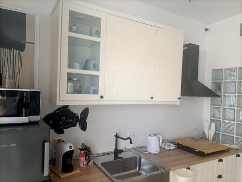 een keuken met witte kasten en een spoelbak bij Casa Vacanze Pesce Palla in Villaggio Azzurro