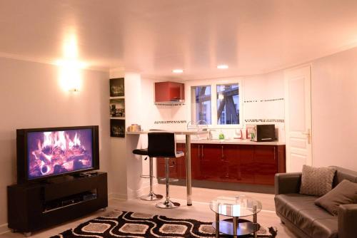ein Wohnzimmer mit einem Sofa und einem Flachbild-TV in der Unterkunft Beau studio meublé 2min du Moulin Rouge in Paris