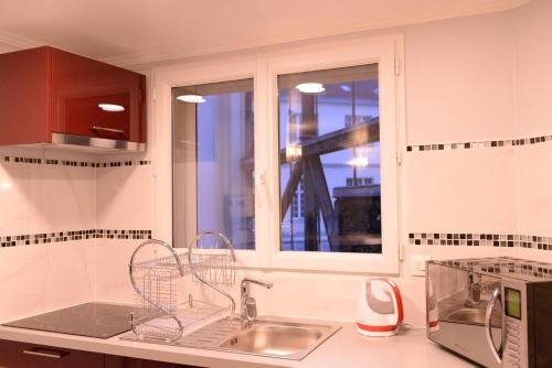 eine Küche mit einem Waschbecken und einem Fenster in der Unterkunft Beau studio meublé 2min du Moulin Rouge in Paris