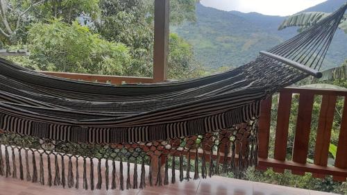 a hammock on a balcony with a view at LA CASA DEL BOSQUE Via SALADITO in La Elvira