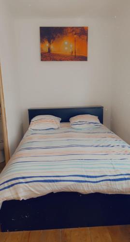 a bed with a striped comforter in a bedroom at Clem in Calais