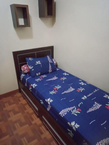 1 cama con edredón azul y almohadas en Apartemen Gateway Cicadas pemandangan Kota Pegunungan BY Sarana Cipta Mahakarya, en Bandung