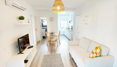 a living room with a white couch and a tv at Caroline's in Vila do Bispo