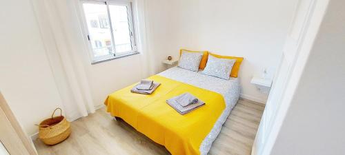 Dormitorio pequeño con cama con manta amarilla en Caroline's, en Vila do Bispo