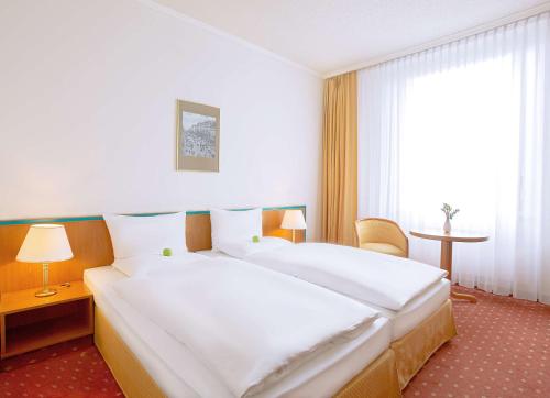 ライプツィヒにあるDorint Hotel Leipzigのベッド2台と窓が備わるホテルルームです。