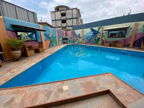 a swimming pool on the roof of a building with a mural at Bays Lodge, Accra in Accra