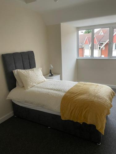 a bedroom with a bed with a yellow blanket on it at Large 4 Bedroom Sleeps 8, Spacious Apartment for Contractors and Holidays near Bedford Centre - 1 FREE PARKING SPACE & FREE WIFI in Bedford