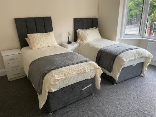 Duas camas sentadas uma ao lado da outra num quarto em Large 4 Bedroom Sleeps 8, Spacious Apartment for Contractors and Holidays near Bedford Centre - 1 FREE PARKING SPACE & FREE WIFI em Bedford