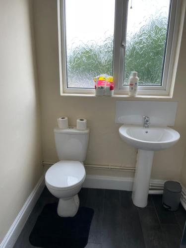La salle de bains est pourvue de toilettes, d'un lavabo et d'une fenêtre. dans l'établissement Large 4 Bedroom Sleeps 8, Spacious Apartment for Contractors and Holidays near Bedford Centre - 1 FREE PARKING SPACE & FREE WIFI, à Bedford