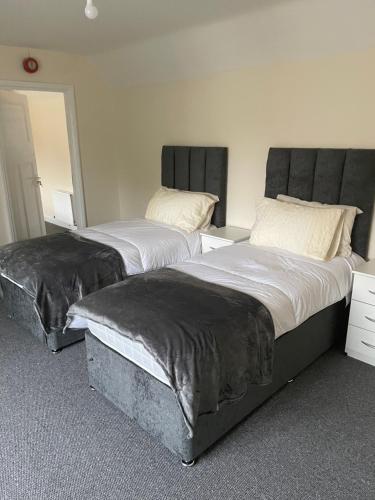 two beds sitting next to each other in a room at Large 4 Bedroom Sleeps 8, Spacious Apartment for Contractors and Holidays near Bedford Centre - 1 FREE PARKING SPACE & FREE WIFI in Bedford
