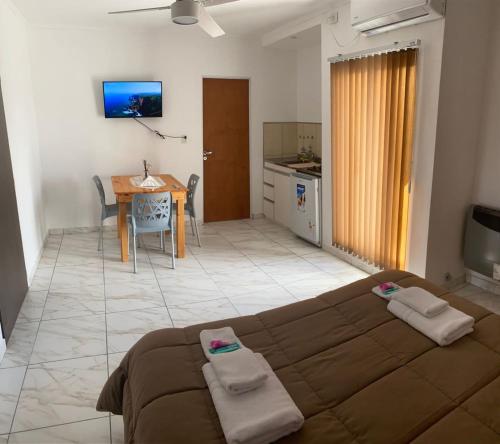 a bedroom with a bed and a kitchen with a table at Apart Los Algarrobos in Marcos Juárez