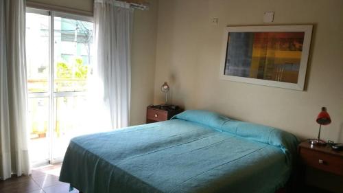 a bedroom with a blue bed and a window at DUPLEX TIERRA DE MAR 2 in San Clemente del Tuyú