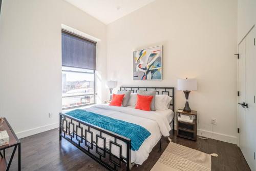 a white bedroom with a large bed with red pillows at The Flats King Bed- EWR/Penn Station in Newark