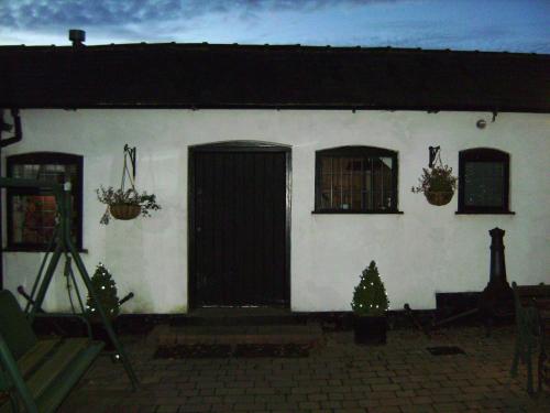 a white house with a black door and windows at Brook Barn B&B in Hale
