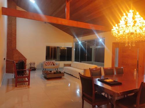 a living room with a dining table and a chandelier at CASA DE CAMPO Banheira, Lareira e Cachoeira in Pedra Azul