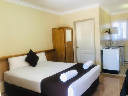 1 dormitorio con 1 cama grande con almohadas blancas en Angel's Rest Motel en Moree