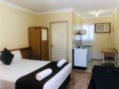 a bedroom with a large white bed and a kitchen at Angel's Rest Motel in Moree