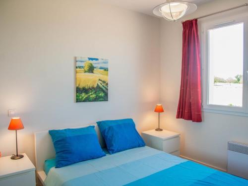 Un dormitorio con una cama azul y una ventana en Les Graves, en Saint-Pierre-Lafeuille
