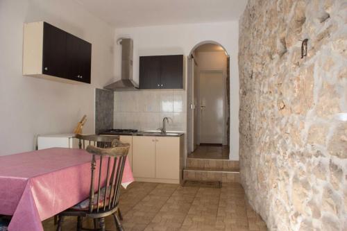 a kitchen with a table and a stone wall at Holiday house with WiFi Novi Vinodolski - 12241 in Novi Vinodolski