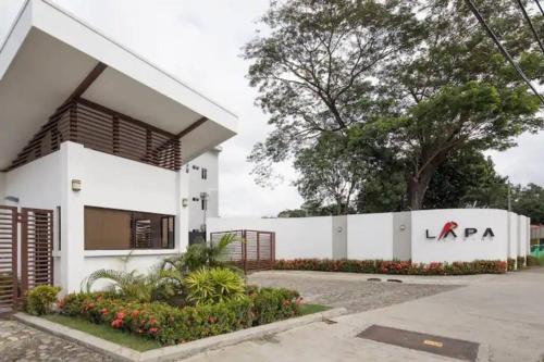 a white building with a sign on it at Lapa Lodge G1 in Jacó