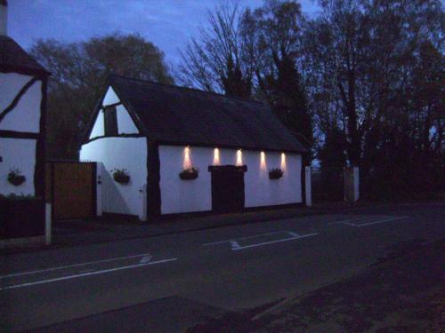 a small white building with lights on it at night at Brook Barn B&B in Hale