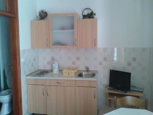 a small kitchen with a sink and a television at Apartments and rooms with parking space Solaris, Sibenik - 12269 in Šibenik