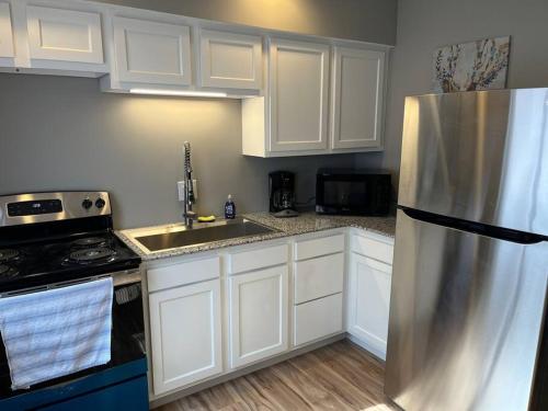 uma cozinha com armários brancos e um frigorífico de aço inoxidável em Carter #4 Two bedroom unit near Xavier Downtown em Cincinnati