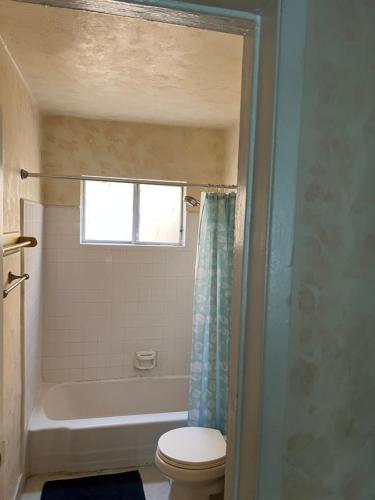 baño con aseo, bañera y ventana en Lovely Berryman Ave Apartment, en Los Ángeles
