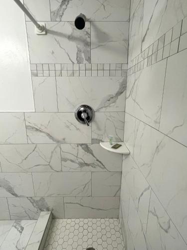 een badkamer met een douche en witte marmeren tegels bij Downtown Inn in Rochester
