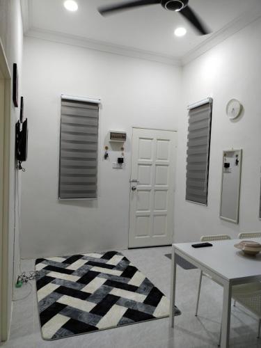 Habitación blanca con mesa y alfombra blanca y negra en Wanna Homestay, en Jertih