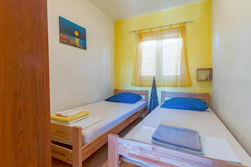 two beds in a small room with a window at Apartments by the sea Basina, Hvar - 11923 in Vrbanj