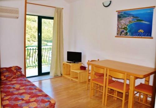 a room with a table and a television and a balcony at Apartments with a parking space Drvenik Donja vala, Makarska - 12297 in Drvenik