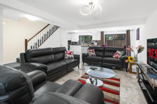 a living room with black leather couches and a table at 2026 Winner of Travelers Award - Four Bedroom Houses & Studio Apartments - HS2 Contractors - NEC - Birmingham Airport - BCU & Aston University - Heartland Hospital - Jaguar - Star City in Birmingham