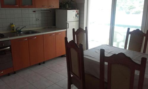 a kitchen with a table with chairs and a refrigerator at Apartments by the sea Zaglav, Dugi otok - 12424 in Zaglav
