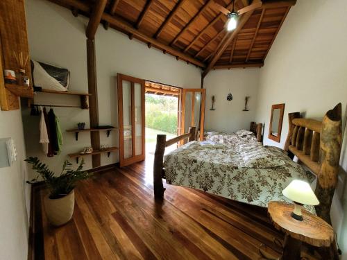 1 dormitorio con 1 cama y suelo de madera en Recanto da Natureza, en Brotas