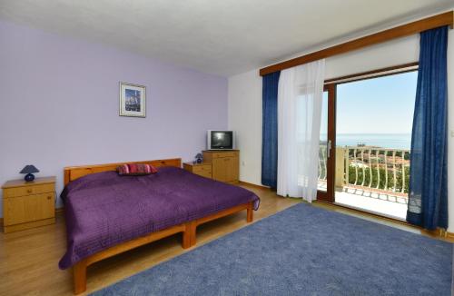 um quarto com uma cama e uma grande janela em Family friendly apartments with a swimming pool Baska Voda, Makarska - 12442 em Baska Voda