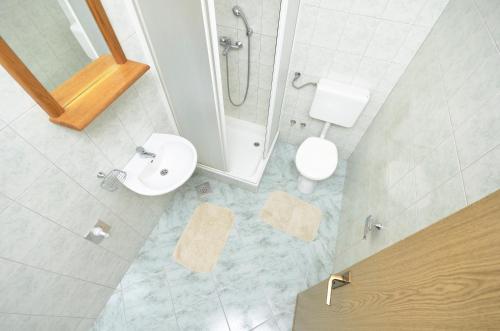 een badkamer met een douche, een toilet en een wastafel bij Family friendly apartments with a swimming pool Baska Voda, Makarska - 12442 in Baška Voda