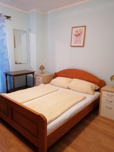 a bedroom with a large bed with a wooden headboard at Apartments and rooms by the sea Kampor, Rab - 12473 in Rab