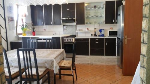 een keuken met zwarte kasten en een tafel en stoelen bij Apartments by the sea Lopar, Rab - 12534 in Lopar