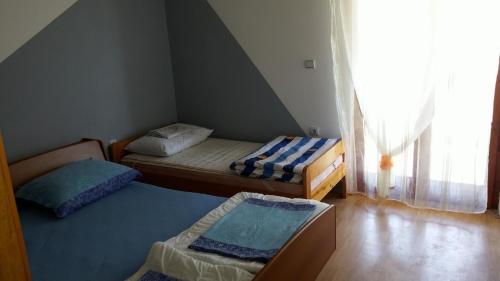 2 łóżka w małym pokoju z oknem w obiekcie Apartments by the sea Lopar, Rab - 12534 w mieście Lopar
