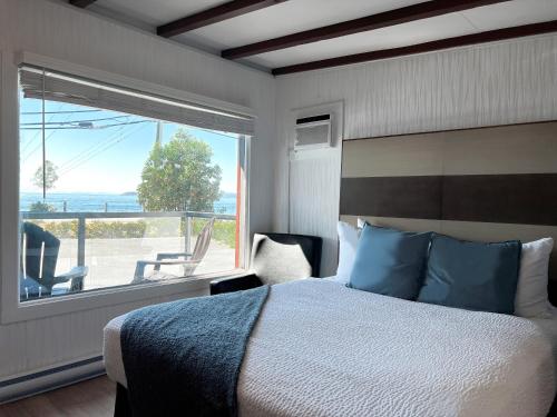 a bedroom with a bed and a large window at Oceanside Villas in Sechelt