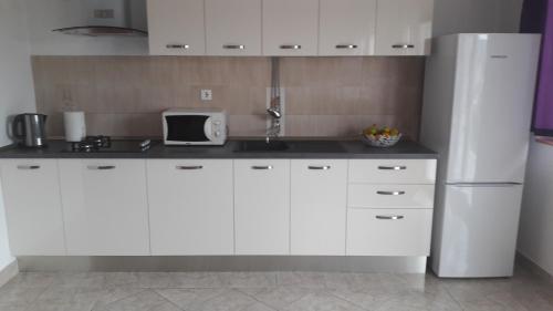 een keuken met witte kasten en een witte koelkast bij Apartments with a parking space Vinisce, Trogir - 12637 in Vinišće