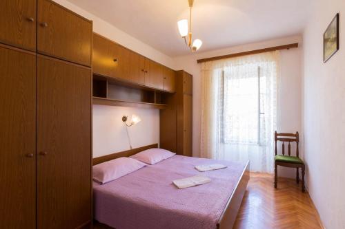 a bedroom with a purple bed with a chair and a window at Apartment Mali Losinj 12634a in Veli Lošinj