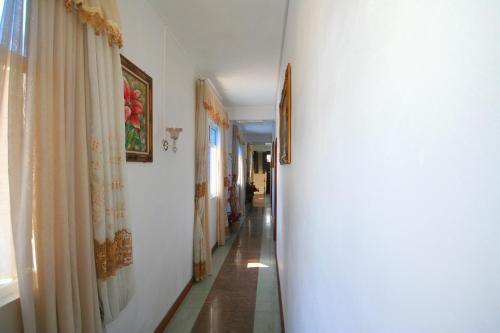 a hallway with white walls and a long hallway with a curtain at 3Ds International Tourist Home in Mahébourg
