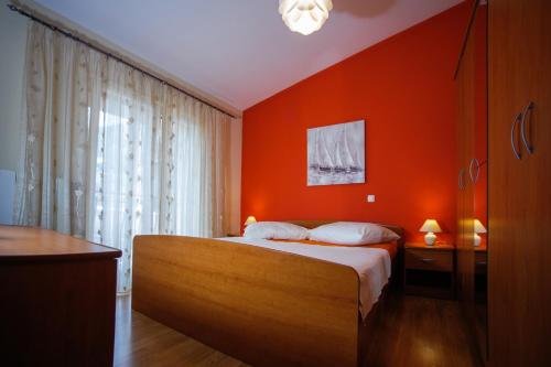 Un dormitorio con una pared de color naranja y una cama en Apartments with a parking space Ostrvica, Omis - 12674, en Gata