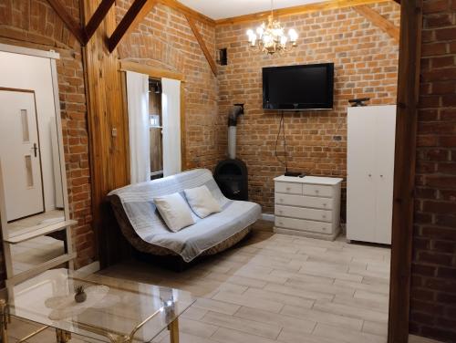 a living room with a chair and a tv on a brick wall at Apartamenty nad Łyną in Olsztyn