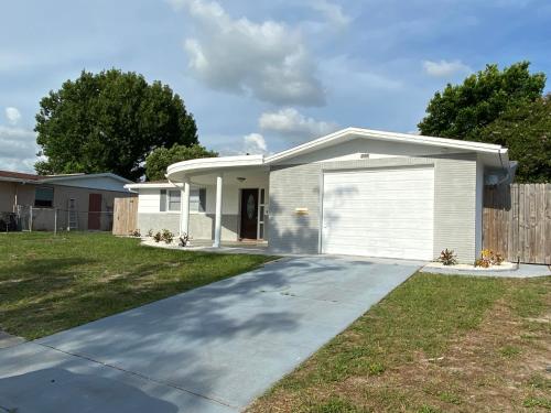 een wit huis met een garage bij Cozy 3-bed home close to beautiful beaches. in New Port Richey