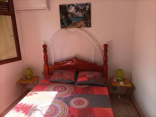 1 Schlafzimmer mit einem Bett mit einer roten Bettdecke und 2 Tischen in der Unterkunft Villa saisonnière Montalegre Lamentin in Lamentin