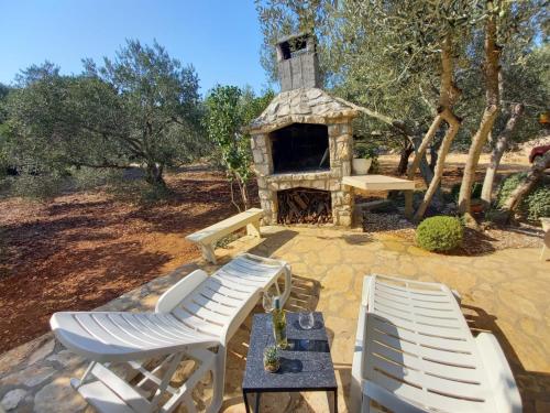 two white chairs and a table and a stone fireplace at Secluded holiday house Cove Nevidjansko Polje, Pasman - 12806 in Neviđane