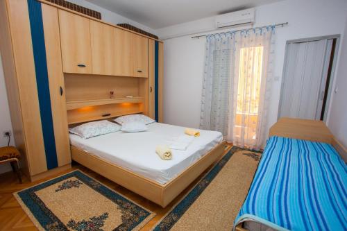 a small bedroom with a bed and a window at Apartments with parking space Podgora, Makarska - 12816 in Podgora